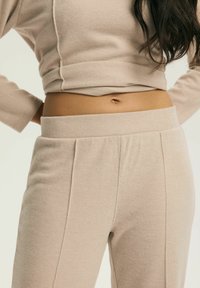 Beżowy prążkowany top i spodnie z dzianiny, z krótkim krojem, elastycznym pasem i widocznymi szwami, wykonane z miękkiego, teksturowanego materiału.