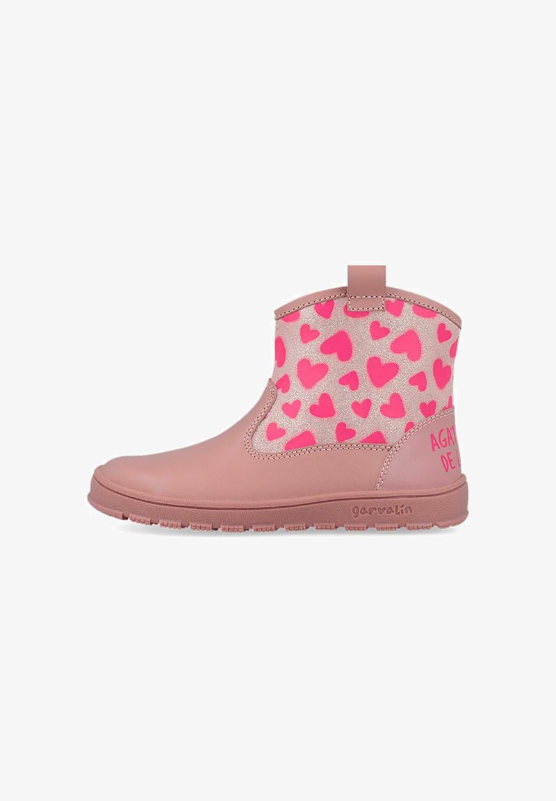 Botas de tobillo rosas con un upper brillante de estampado de corazones, parte inferior de goma suave y suela texturizada. Presenta una pestaña para facilitar el uso.