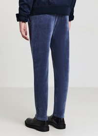 Pantaloni in corda blu navy con una texture morbida, vestibilità dritta e vita elastica, abbinati a stivali neri in pelle alla caviglia.