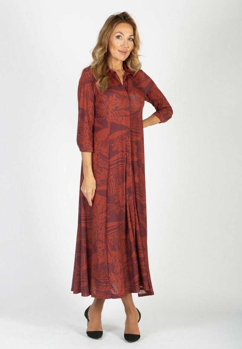 Bordowa sukienka midi w kwiaty z rękawami do trzech ćwiartek, kołnierzykiem i rozkloszowanym dołem. Gładki materiał z subtelnym wzorem. Czarne szpilki.