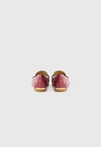 Red leather slip-on shoes with a low profile, rounded toe, and beige rubber sole. Smooth texture with minimal stitching details.