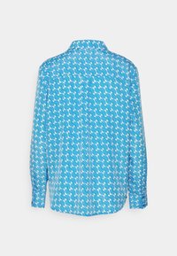 Camicia a maniche lunghe con un motivo a onde in blu e bianco. Realizzata in tessuto leggero, con colletto abbottonato e yoke posteriore discreto.