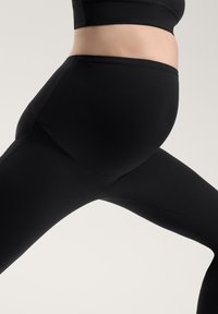 Zwarte leggings van rekbaar materiaal, met een hoge tailleband en een gladde textuur, ontworpen voor comfort en flexibiliteit tijdens activiteiten.