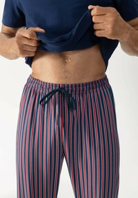 Pantaloni da pigiama a righe con un motivo a righe verticali blu navy, rosso e bianco, vita elasticizzata e cordino regolabile. Materiale in cotone morbido.