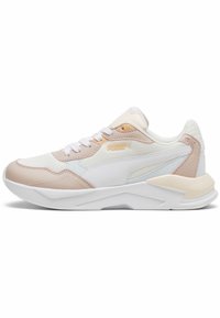 Sneaker blanche et beige de Puma avec des détails en maille et en cuir, fermeture à lacets et semelle rembourrée, présentée de côté sur un fond blanc.