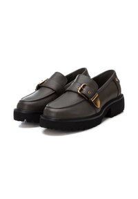 Zapatos de piel tipo mocasín en gris oscuro con un acento de hebilla dorada. Cuentan con una suela de perfil bajo y una textura de goma negra antideslizante.