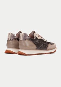 Zapatillas marrones y beige que combinan materiales de cuero y textil, con una superficie texturizada y una suela de goma. Marca en el talón.