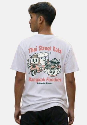 Mann mit weißem T-Shirt mit Cartoon-Tuk-Tuk und Nudelschüssel, Text "Thai Street Eats Bangkok Foodies Authentic Flavors" auf dem Rücken.