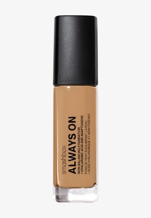 Flacon de fond de teint liquide Smashbox Always On avec bouchon noir en teinte beige moyen, étiqueté avec le nom du produit et ses caractéristiques.