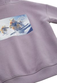 Lila pulóver, amelyen három medve snowboardozik egy nyomtatott grafikával, sima textúrával és bordázott mandzsettákkal és aljjal.