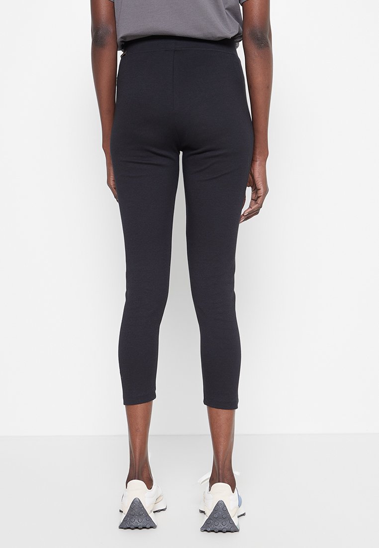 Leggings negros ajustados con cintura alta, de longitud corta, textura suave y material elástico, adecuados para vestimenta casual o deportiva.