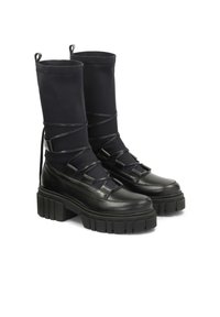 Botas de tobillo negras con una base de cuero texturizado y una parte superior de tela elástica negra, con suelas gruesas de plataforma y cordones entrecruzados.