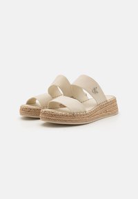 Béžové espadrilky na platformě s dvěma širokými textilními pásky, podešví obalenou provázkem a detailem loga na jednom pásku.