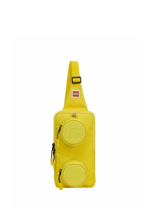 Sacoche LEGO jaune avec bandoulière ajustable et deux poches rondes zippées embossées du logo LEGO à l'avant.
