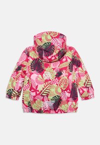 Chaqueta con capucha colorida sobre un fondo rosa que presenta grandes patrones de hojas vibrantes en verde, negro y blanco. Detalles en los puños elásticos.