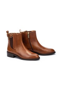 Botas de tobillo de cuero marrón con puntera redondeada, cremallera lateral, paneles elásticos y una correa con detalle de hebilla. Diseño de tacón bajo y plano.