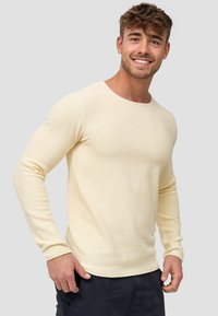 Langärmliger Rundhalsausschnitt-Pullover aus hellgelbem Strickstoff, mit einem strukturierten Muster und schmalen Ärmeln. Glatte Oberfläche, lässiges Design.
