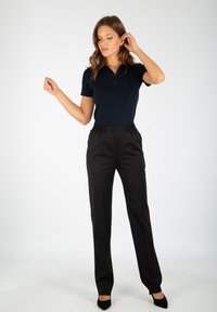 Polo shirt marine à manches courtes, associé à un pantalon noir ajusté avec taille élastique, porté avec des escarpins noirs à bout pointu.