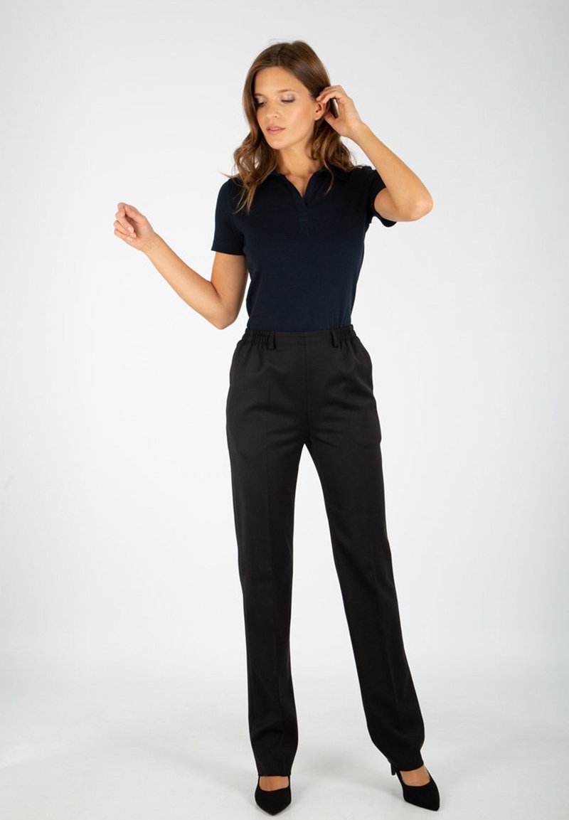 Polo shirt marine à manches courtes, associé à un pantalon noir ajusté avec taille élastique, porté avec des escarpins noirs à bout pointu.
