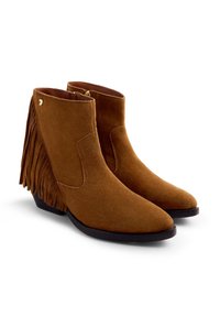 Botines de ante marrón con detalles de flecos, punteras en punta y tacón bajo. Incluyen una cremallera lateral para facilitar su uso.