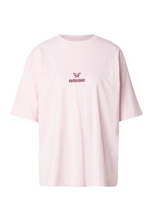 Lys rosa bomulls-T-skjorte med korte ermer og rund hals. Forsiden har brunt grafisk tekst og sommerfugl-logo.