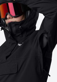 Černá zateplená bunda s vysokým límcem, zipovými kapsami a nastavitelnou kapucí. Obsahuje měkkou vnitřní podšívku a značkový akcent.