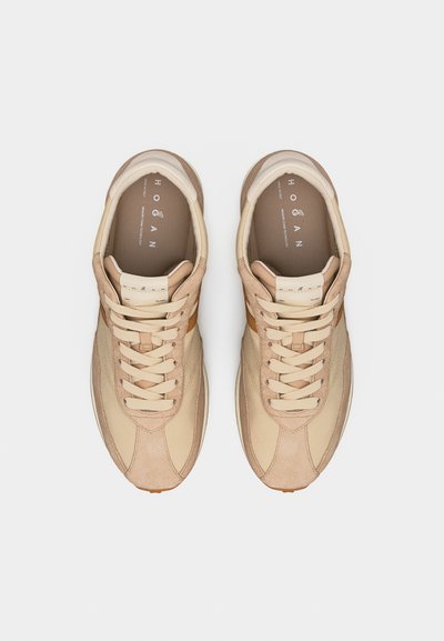 Paire de baskets beiges et marron clair à lacets avec des panneaux en daim et en cuir, vues de dessus sur un fond clair uni.