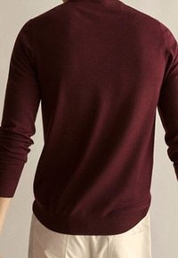 Maglione a maglia bordeaux con maniche lunghe, scollatura rotonda e polsini e orlo a coste, che mette in risalto una texture liscia.