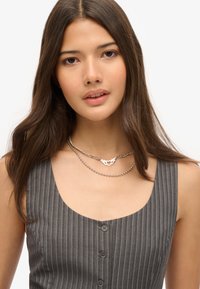 Grijs gestreepte jurk met een ronde halslijn en knoopdetails, gecombineerd met gelaagde zilveren kettingen met een hanger en kralen.