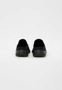 Zwarte sport schoenen met een ademend mesh bovendeel, gevoerde kraag en een gestructureerde buitenzool voor grip, met een minimalistisch ontwerp.