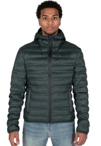 Giacca a vento verde con zip frontale, colletto alto e logo sul petto a sinistra. Tessuto leggero e testurizzato con un design aderente.