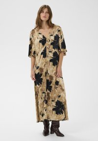 Rochie lungă din material cu model, cu imprimeuri mari florale negre pe un fundal bej. Decolteu în V și mâneci până la cot.