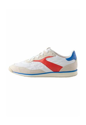 Chaussure de sport avec une tige en cuir blanc, des accents rouges et bleus, un bout en suède et une semelle en caoutchouc. Caractéristiques de détails texturés et de laçage traditionnel.
