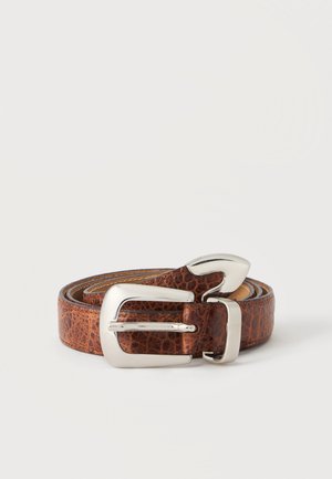 Opgerolde bruine leren riem met een gestructureerd patroon en een glanzende zilverkleurige metalen gesp op een effen lichte achtergrond.