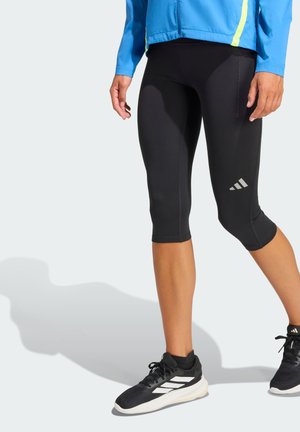 Black athletic capri leggings with a fitted design, featuring a side seam pocket and a reflective striped accent on the lower leg.