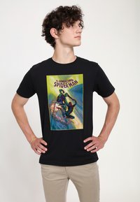 Sort bomulds t-shirt med et grafik i tegneseriestil af Spider-Man og en skurk mod en byberetning med klare grønne og blå farver.