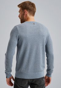 Hellblauer, strukturierten Strickpullover mit langen Ärmeln, gerippten Bündchen und Saum sowie einem kleinen Logodetail im Nackenbereich.