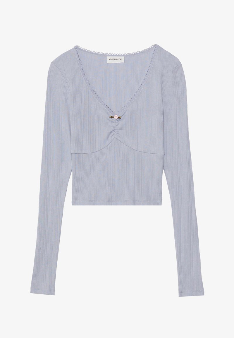 Light blue long-sleeve cropped top with ribbed texture, V-neckline, gathered front detail, and a decorative pin at the center.