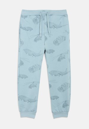 Világoskék melegítőnadrág járművekkel nyomtatott mintával, többek között autókkal és repülőgépekkel, elasztikus derékpánttal és mandzsettás szárvégekkel.