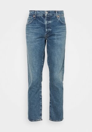 Blauwe denim jeans met ontwerp met vijf zakken, knoop- en ritssluiting en rechte pijpen tegen een witte achtergrond.