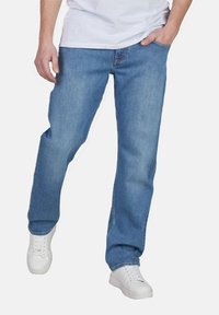 Jeans de mezclilla azul claro con un diseño de pierna recta, cinco bolsillos y detalles de costura visibles. Combinados con zapatillas blancas.