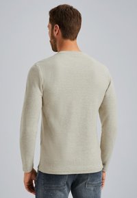 Long-sleeve, light grey shirt with a round neckline, made of soft fabric, featuring casual fit and side slits at the hem.