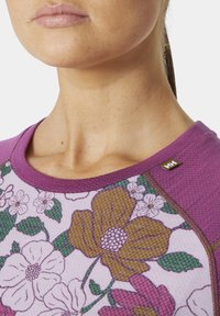 Fialová košile s květinovým vzorem a krátkými rukávy, s kulatým výstřihem a texturovanou tkaninou. Jemný detail loga na límci.