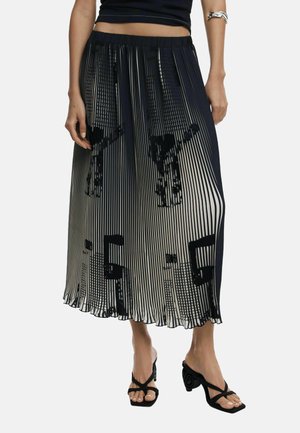 Black and white pleated skirt with a graphic print, featuring a stretchy waistband and a flowy design, paired with black strappy sandals.