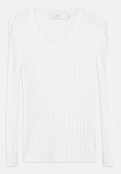Haut en tricot côtelé blanc à manches longues et décolleté en V. Texture douce et design ajusté. Présente des lignes verticales subtiles et des fentes latérales.