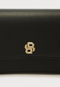 Carteira preta de couro com superfície texturizada. Emblema de logótipo em tom dourado e detalhe de costura visível ao longo da borda. Design compacto.