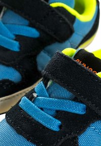 Sneaker blu e neri con tessuto strutturato, dotati di una fascia in velcro e accenti gialli luminosi, punta arrotondata e lacci a contrasto.