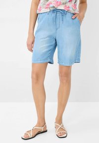 Shorts in denim azzurro con vita elastica e coulisse, dotati di tasche laterali e fit rilassato, che terminano poco sopra il ginocchio.