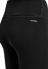 Zwarte legging gemaakt van glad, rekbaar materiaal. Met een hoge tailleband en een klein wit logo. Naaddetails langs de zijkanten.