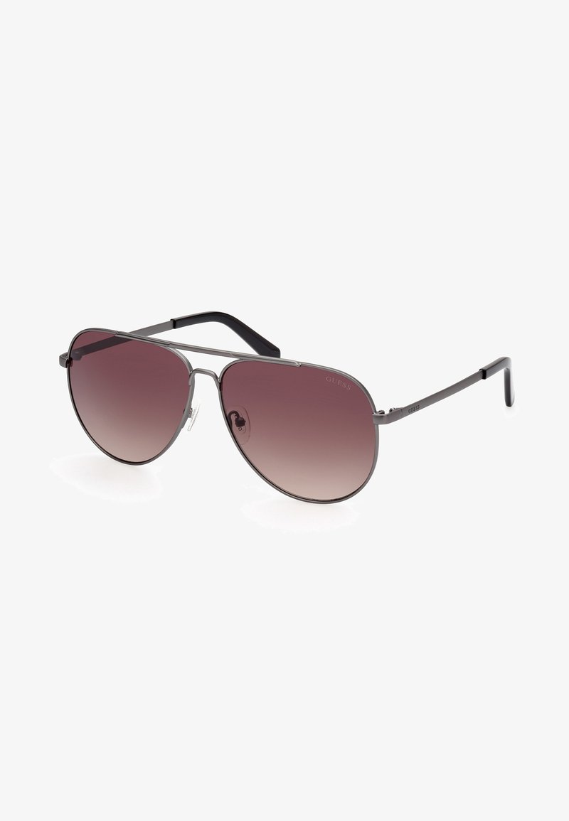Metall Aviator-Sonnenbrille mit dunklen Übergangslinsen, einem dünnen silbernen Rahmen und schwarzen Bügeln, die seitlich ein dezentes Logo tragen.